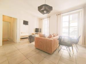 a living room with a couch and a table and chairs at Appartement Le Cœur de Nîmes Secteur Arènes Parking Offert ! in Nîmes