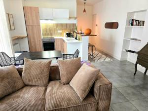 a living room and kitchen with a couch and a table at Appartement Le Cœur de Nîmes Secteur Arènes Parking Offert ! in Nîmes