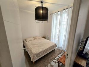 a small bedroom with a bed and a chandelier at Appartement Le Cœur de Nîmes Secteur Arènes Parking Offert ! in Nîmes