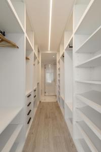 a walk in closet with white shelves and a hallway at Lux House in Leiria