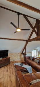 een woonkamer met een plafondventilator en een bank bij Les Granges Indigo in Fossemagne
