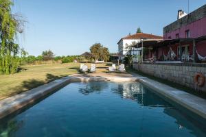 a swimming pool with two chairs and a house at Casa das Jardas in Idanha-a-Nova