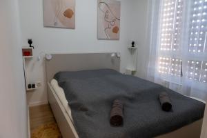 トゥズラにあるApartman Amorの靴下が置かれたベッドのある白い寝室