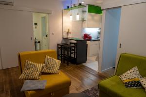 a living room with two chairs and a kitchen at Apartman Amor in Tuzla