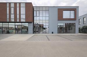 格涅兹诺iNTEC NOCLEGI的一座带玻璃窗和庭院的大型建筑