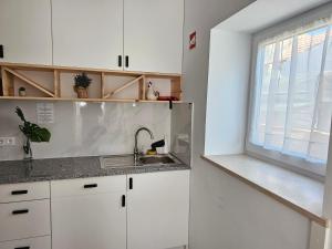 a kitchen with white cabinets and a sink and a window at Curtido House in Aveiro