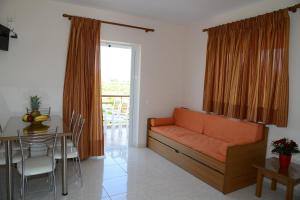 a living room with an orange couch and a table at Maria's Filoxenia Suites in Drepana