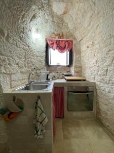 una piccola cucina con un lavandino e una finestra di Nidadi Trulli d'Itria a Martina Franca