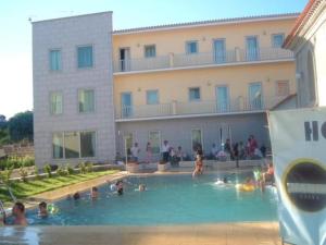 eine Gruppe von Personen in einem Schwimmbad vor einem Gebäude in der Unterkunft Hotel Portas Do Dao in Penalva do Castelo