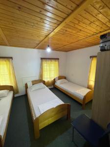 a room with three beds and a wooden ceiling at Motina River Guesthouse in Tropojë