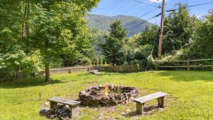 una hoguera en un campo con dos bancos en Smoky Mountain Mecca by Carolina Mornings, en Waynesville