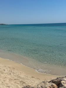 a sandy beach with the ocean and rocks at Core Salentino Rooms in Campomarino