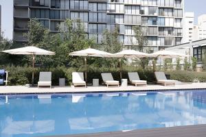 a pool with lounge chairs and umbrellas next to a building at Sao Paulo Vertical in Guadalajara