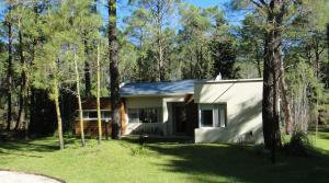 a small white house in the woods at Guindo Cariló in Carilo