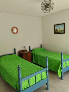 a bedroom with two beds with green sheets and a chandelier at Guindo Cariló in Carilo