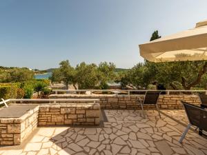 een patio met een stenen muur en stoelen en een parasol bij Villa On The Beach in Pirovac