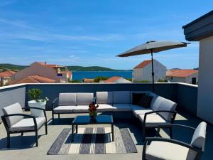 a patio with a couch and chairs and an umbrella at VILLA OCEAN BREEZE with pool in Zaglavice