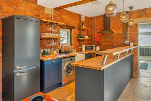 a kitchen with a washer and dryer and a brick wall at Luxury Escape with Cinema, Pool Table & Darts in Leeds