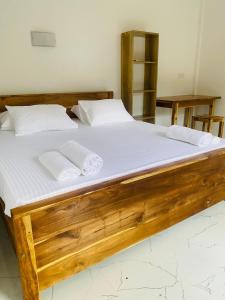 a large wooden bed with two pillows on it at AG Villas Arugambay in Arugam Bay +11 photos