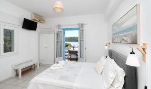 Biała sypialnia z łóżkiem i balkonem w obiekcie Anastasia Studios & Apartments w mieście Panormos