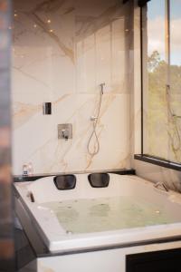 a bathroom with a bath tub with a window at Chalé Encantos do Frade in Bom Retiro +37 photos