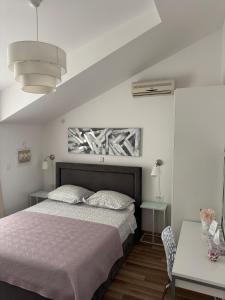 a white bedroom with a bed and a table at Apartments Roko in Kaštela