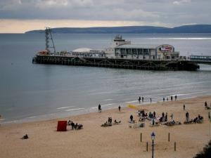 a beach with people on the sand and boats in the water at The Manchester Hotel in Bournemouth