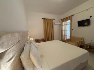 a bedroom with a large white bed with pillows at Asteri Hotel in Livadi