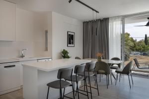 a white kitchen with a table and chairs at Phaedrus Living Travertine Residences 102 in Strovolos