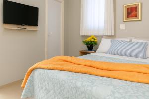 sypialnia z łóżkiem z pomarańczowym kocem i telewizorem w obiekcie Pousada Estrela Dourada w mieście João Pessoa