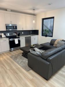 a living room with a black couch and a kitchen at Delux 2 bedroom suite in White Rock