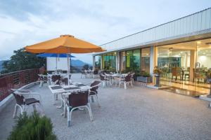 a patio with tables and chairs and an umbrella at Hotel Sunway Murree in Murree