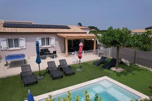a backyard with chairs and a swimming pool and a house at En Ardèche, maison de vacances l'Odyssée climatisée avec sa piscine privée et chauffée in Joyeuse