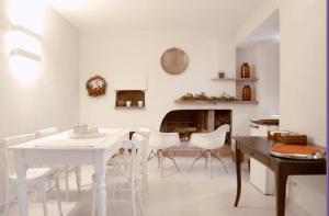 een witte eetkamer met een tafel en stoelen en een open haard bij B&B Gocciaverde in Rocchetta a Volturno