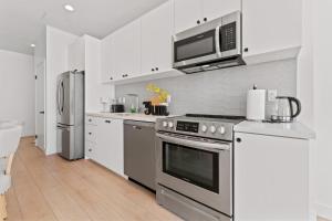 Una cocina con estufa de acero inoxidable y microondas. en Modern Retreat in Koreatown - Perfect for Your LA Stay!, en Los Ángeles 11 fotos más