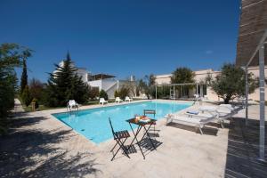 a swimming pool with chairs and a table next to it at Masseria Agriturismo Faresalento in Gallipoli