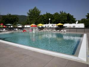 a swimming pool with a fountain with chairs and umbrellas at Mobil home au bord du lac de Foix in Foix