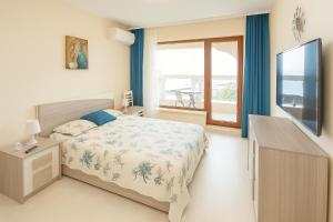 ein Schlafzimmer mit einem Bett und einem Fenster und einem Fernseher in der Unterkunft La Mer Sea View & Beachfront Apartment in Warna