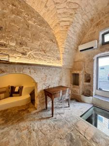 a stone walled room with a table and a bed at Bianca Ostuni in Ostuni