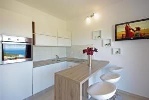 a kitchen with white cabinets and a counter with flowers at Apartments Herceg in Makarska