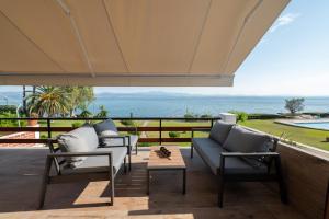 a patio with chairs and a table and a view of the ocean at Veya Suite - Private Beach & Pools in Eretria