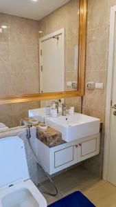 een badkamer met een wastafel, een toilet en een spiegel bij ห้องใหม่ใกล้ทะเล in Jomtien Beach