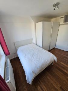 a small bedroom with a white bed and wooden floors at Flat in Hammersmith - Close to tube station in London