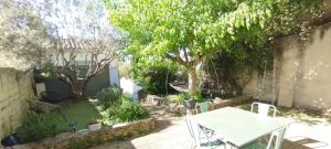 a garden with a table and chairs and trees at Bel appartement du centre ancien in Beaumes-de-Venise