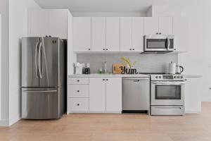 a kitchen with white cabinets and a stainless steel refrigerator at Stylish LA Getaway near Downtown - Prime Location on Wilshire Blvd! in Los Angeles