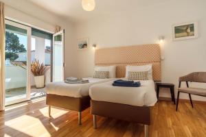 a bedroom with a bed and a chair and a window at LV Premier Meco/Lagoa LA1 in Sesimbra