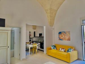 a living room with a yellow couch and a kitchen at Pozzelle Holiday House in Zollino