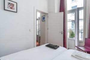 Un dormitorio con una cama blanca y una silla roja. en LV Premier Apartments Baixa- FI, en Lisboa