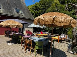 a group of tables and chairs under umbrellas on a deck at Maison du WHITE ROCK in Saint-Jouan-des-Guérets