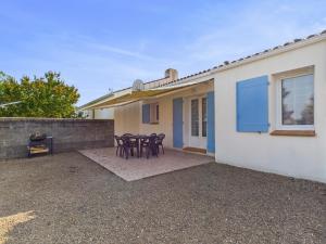 eine Terrasse mit Tischen und Stühlen vor einem Haus in der Unterkunft Maison de vacances pour 4, St-Hilaire-de-Riez in Saint-Hilaire-de-Riez